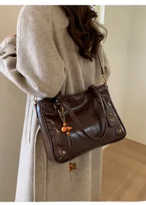 Detail of dark brown wax leather tote bag with vintage texture and beaded tassel charm