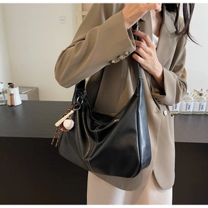 Detail of black large hobo bag with white stitching and baseball bat charm detail