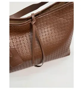 Gros plan sur la texture en cuir tressé marron foncé et l'étiquette du cabas