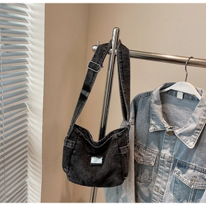 Détail du sac bandoulière en jean noir délavé avec plaque métallique et sangle réglable