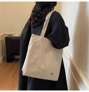Sac fourre-tout minimaliste en toile beige porté à l'épaule pour référence de taille