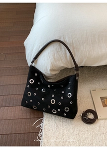 Detail of vintage tote bag featuring silver eyelets and brown leather handle on soft rug