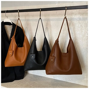 Three leather hobo bags in caramel, black, and coffee hanging on a display stand