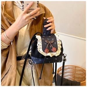 Détail du mini sac à dos vintage avec dentelle, motifs floraux et nœud de cerise
