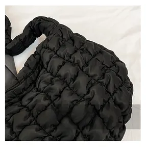 Détail de la texture matelassée noire et de la bandoulière froncée sur un sac cabas