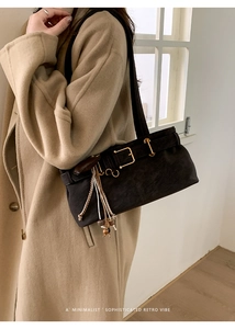Detail of retro dark brown suede shoulder bag with gold buckle and tassel accessory