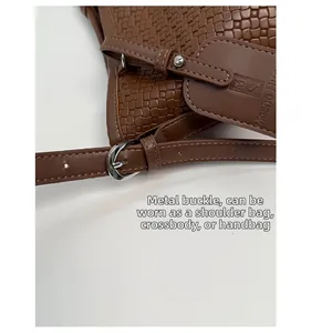 Détail d'un sac à main marron foncé à texture tissée avec boucle et étiquette cuir