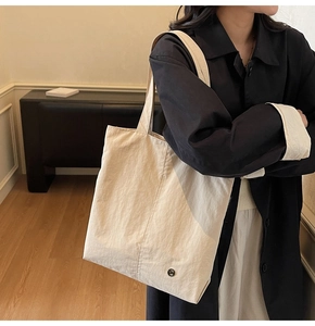 Détail d'un sac cabas imperméable crème avec bouton décoratif noir et texture de tissu