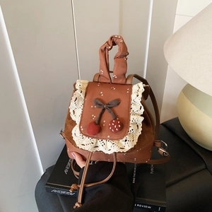 Détail d'un sac à dos vintage marron avec dentelle blanche, cerises et motifs floraux
