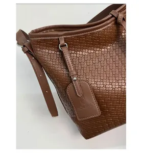 Détail de la texture en cuir tressé marron foncé d'un grand sac cabas avec étiquette