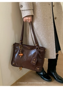 Detailed view of deep brown vintage leather tote with tassel and brand tag on strap