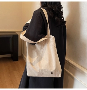 Détail d'un grand sac cabas beige en nylon imperméable avec bouton en métal et bandoulière large