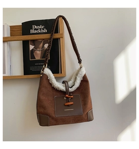 Detail of suede dumpling bag featuring sheepskin trim and vintage horn buckle closure