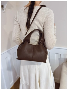 Detail of dark brown lychee pattern leather bucket bag with top handle and metal strap
