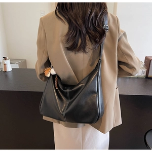 Détail d'un sac hobo noir avec coutures blanches et bandoulière réglable