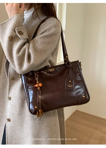 Detail of vintage brown leather tote bag with unique wood bead tassel and gold logo