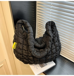 Détail du sac fourre-tout matelassé noir avec étiquette jaune et fermeture éclair