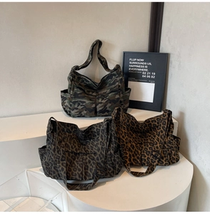 Detail of three leopard and camo canvas bags with multi-pockets on white stands