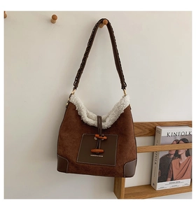 Detail of plush dumpling bag featuring brown suede, faux shearling trim and horn buckle