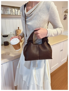 Détail de la texture en cuir marron et de la bandoulière amovible du sac seau hobo