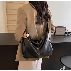 Close-up of black hobo tote bag with white stitching and decorative baseball charm
