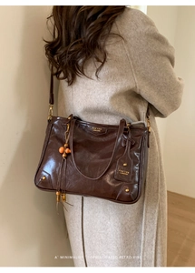 Macro shot of dark brown polished leather tote with vintage texture and gold brand logo