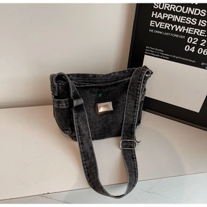 Détail du sac en jean noir délavé vintage avec plaque logo en métal et poche latérale