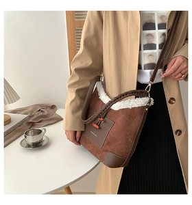 Detail of plush faux fur trim and brown suede texture on a crossbody dumpling bag