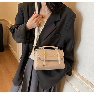 Detail of beige vintage satchel showing lychee texture leather and gold buckle closure