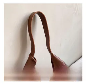 Detailed close-up of brown pebbled leather handle and fine stitching on shoulder bag