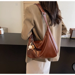 Detail of a large brown tote bag with smooth texture and baseball theme charm accessory