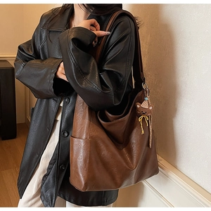 Sac fourre-tout en cuir marron avec breloque d'ours, présenté par un mannequin en studio