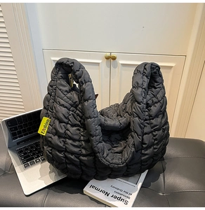 Détail du sac cabas matelassé noir avec étiquette jaune et texture en nylon brillant