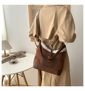 Brown frosted leather tote with white fleece trim and woven handles in cross-body view