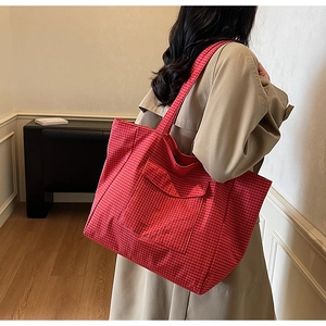 Detailed side view of a red and white checkered tote bag with large front pocket