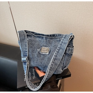 Détail du sac bandoulière en denim bleu avec bords effilochés et plaque en métal chic