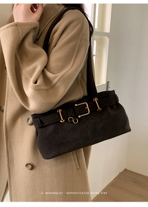 Close-up of minimalist black matte underarm bag with gold metal buckle and retro style