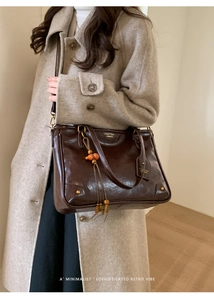 Detail of retro dark brown tote bag with metal buckle and wooden bead tassel accessory