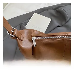 Detail of silver metallic hardware and smooth zipper on brown leather tote bag