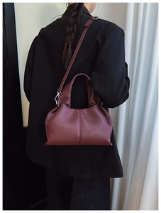 Detail of burgundy lychee grain leather bag with top handle and adjustable shoulder strap