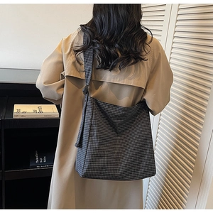 Detail of checkered canvas tote bag showing the adjustable strap and geometric pattern