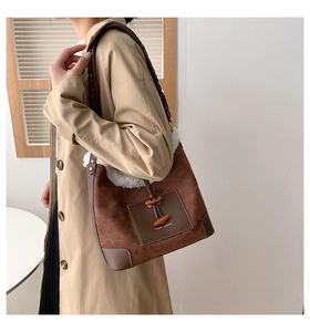 Detail view of suede hobo bag with faux fur trim, wooden horn buckle, and woven strap