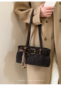 Detail of vintage textured shoulder bag with buckle strap and heart-shaped charm