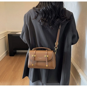 Brown litchi leather satchel bag featuring gold hardware shown on a model's shoulder