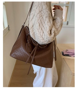 Gros plan sur la texture en cuir tressé marron foncé et la bandoulière du sac cabas femme