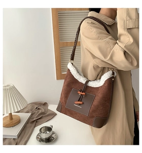 Detail view of brown suede crossbody bag featuring white faux shearling trim and toggle button