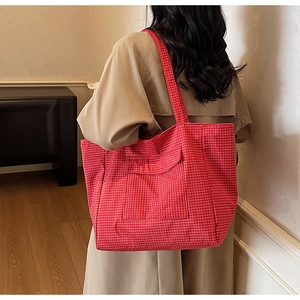 Rear view of a model wearing the large red checkered tote bag for size reference
