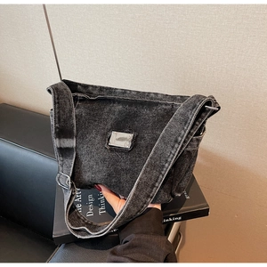 Détail du sac à épaule en denim gris délavé avec plaque logo et bandoulière réglable
