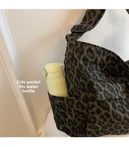 Detail shot of the canvas tote side pocket holding a water bottle for storage capacity