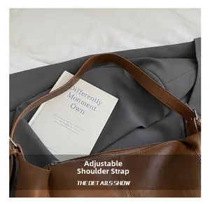 Detail view of the brown leather bag showing adjustable shoulder strap and metal buckle